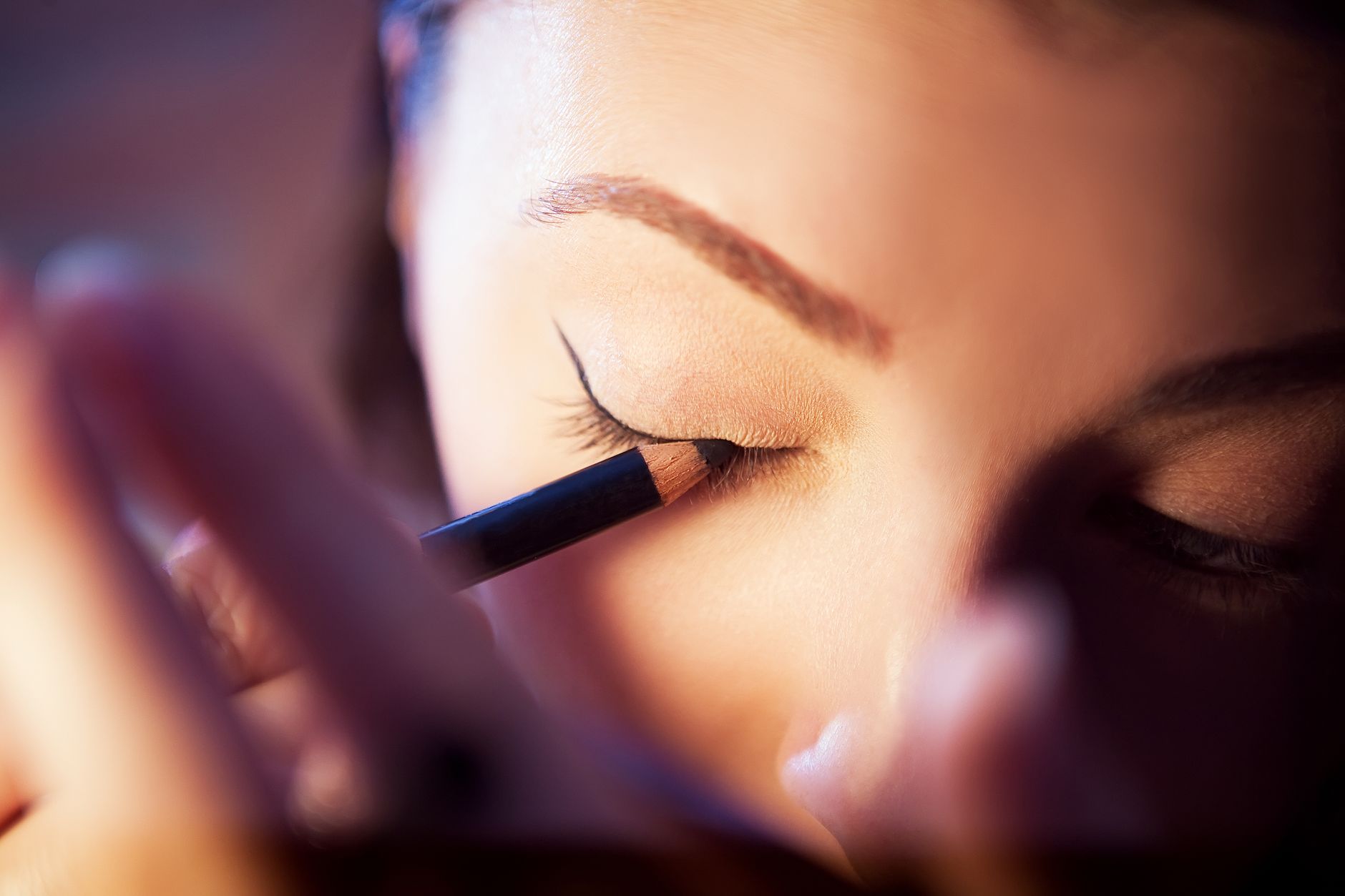 A woman applying eyeliner in a detailed close-up of an eye-focused beauty routine.