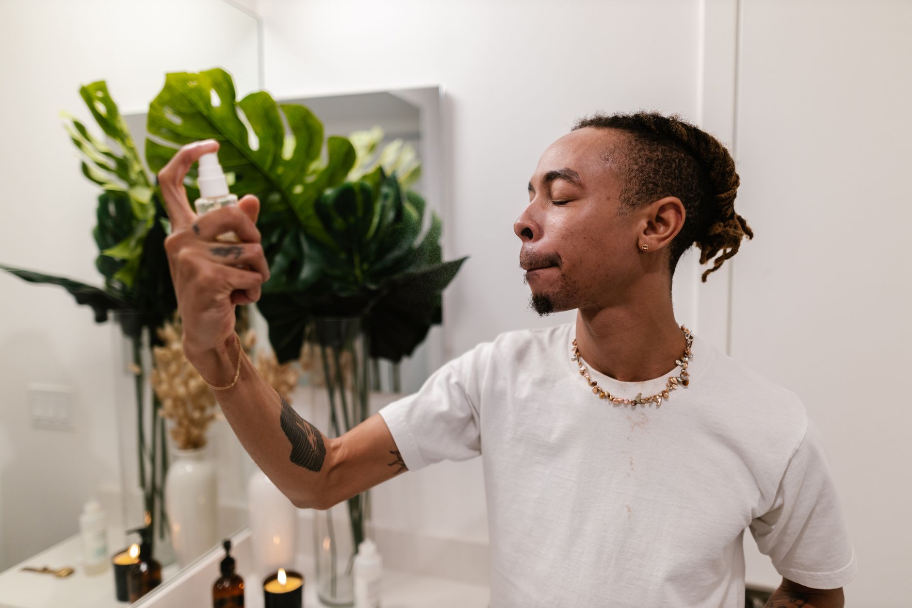 Man using skincare spray in a modern bathroom setting, focusing on personal hygiene.